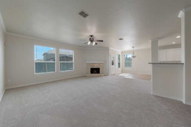 unfurnished living room with visible vents, ornamental molding, baseboards, light colored carpet, and a ceiling fan