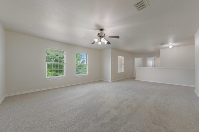 unfurnished room with light colored carpet, a ceiling fan, baseboards, and visible vents
