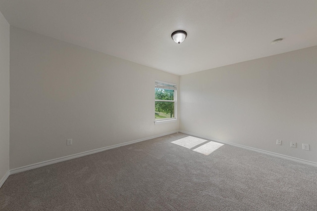carpeted empty room featuring baseboards