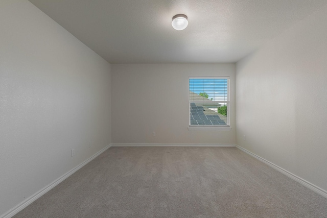 empty room with baseboards and light colored carpet