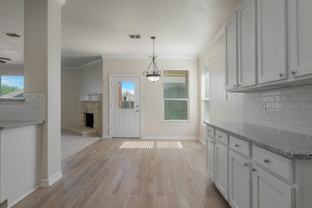 interior space with ornamental molding, light wood finished floors, and visible vents