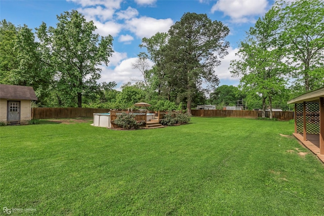 view of yard featuring a storage shed, a deck, an outbuilding, and a fenced backyard