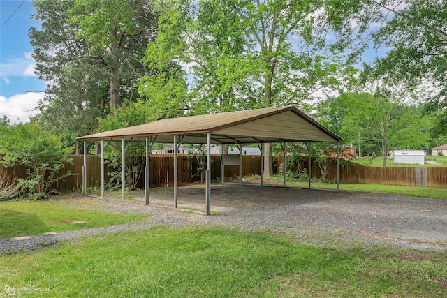 view of vehicle parking with a detached carport, fence, and driveway