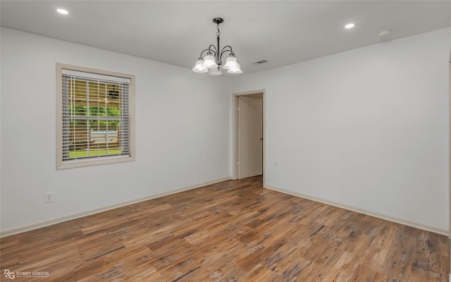 empty room with recessed lighting, a chandelier, wood finished floors, and visible vents