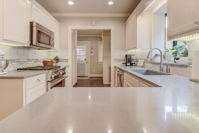 kitchen with crown molding, a sink, light countertops, stainless steel appliances, and decorative backsplash