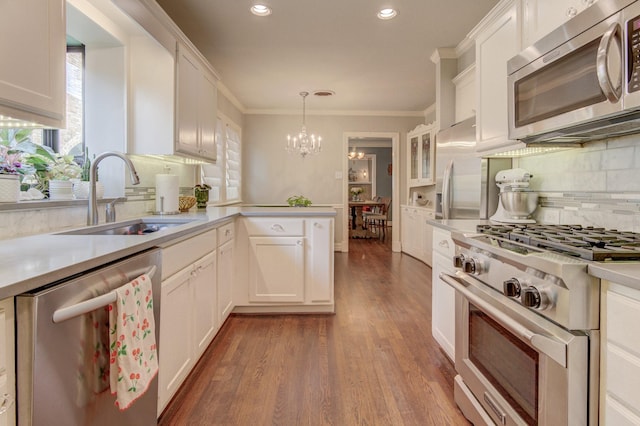 kitchen featuring dark wood finished floors, a sink, an inviting chandelier, stainless steel appliances, and white cabinetry