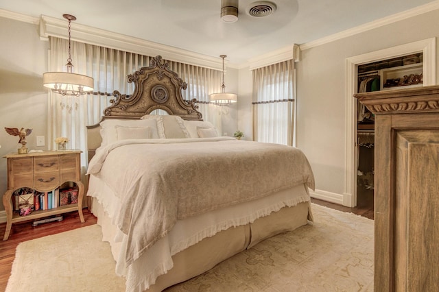 bedroom featuring visible vents, ornamental molding, baseboards, and wood finished floors