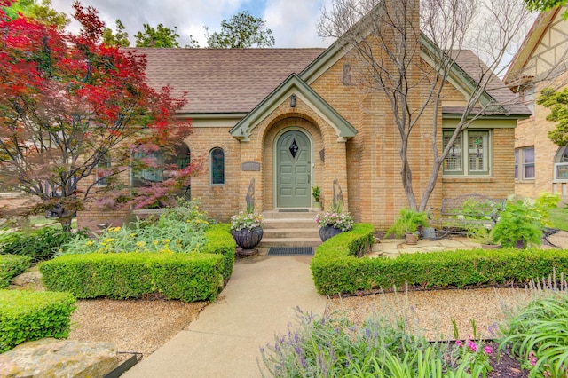 tudor home with brick siding and a shingled roof
