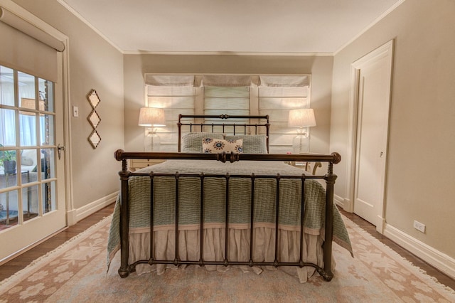 bedroom with crown molding, baseboards, and wood finished floors