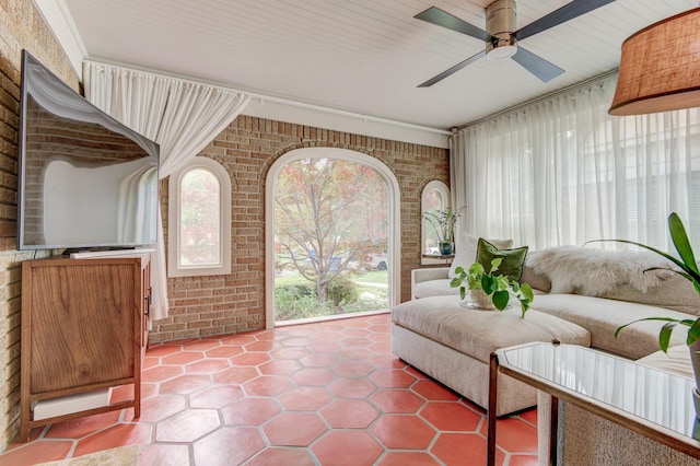 interior space with ceiling fan and brick wall