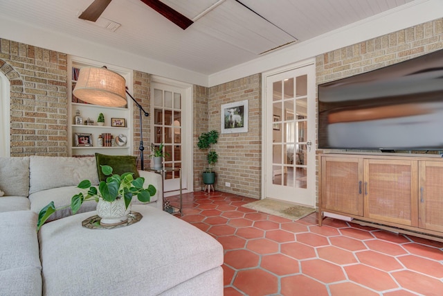 living area with ceiling fan, tile patterned flooring, and brick wall