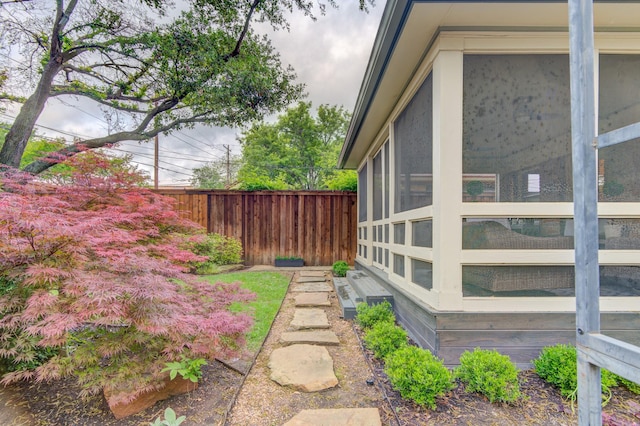 view of home's exterior with fence and a sunroom