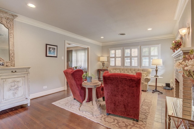 living area with baseboards, ornamental molding, a brick fireplace, and wood finished floors