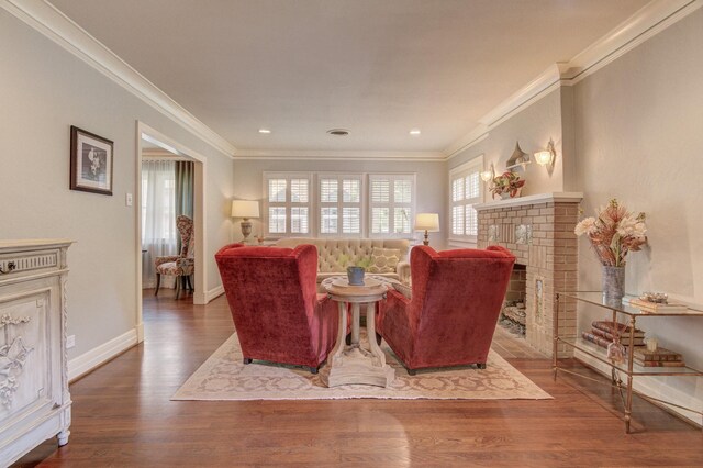 living area featuring crown molding, baseboards, a brick fireplace, and wood finished floors