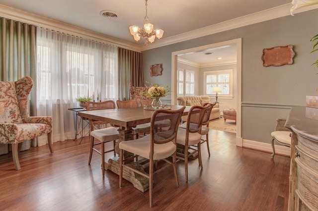 dining room featuring visible vents, wood finished floors, baseboards, an inviting chandelier, and ornamental molding