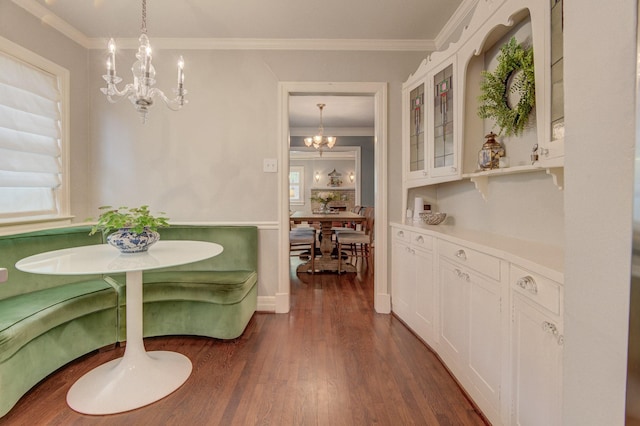 dining space with dark wood-style flooring, a notable chandelier, and ornamental molding