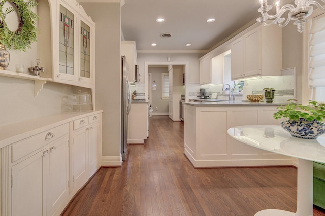 kitchen featuring freestanding refrigerator, white cabinetry, dark wood-type flooring, ornamental molding, and glass insert cabinets