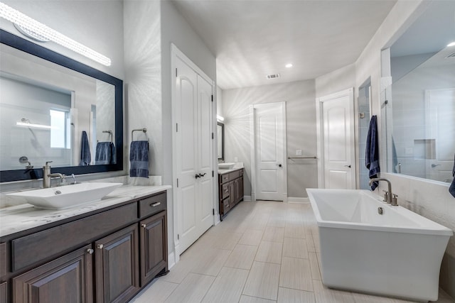 1110 Holford Dr, Frisco, TX 75036 - full bathroom with visible vents, a freestanding bath, walk in shower, two vanities, and a sink