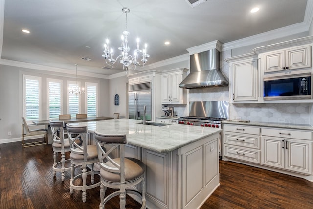 1110 Holford Dr, Frisco, TX 75036 - kitchen featuring wall chimney range hood, dark wood-style flooring, an inviting chandelier, a sink, and built in appliances