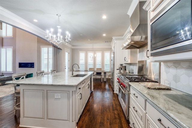 1110 Holford Dr, Frisco, TX 75036 - kitchen with wall chimney range hood, an inviting chandelier, a sink, premium appliances, and ornamental molding