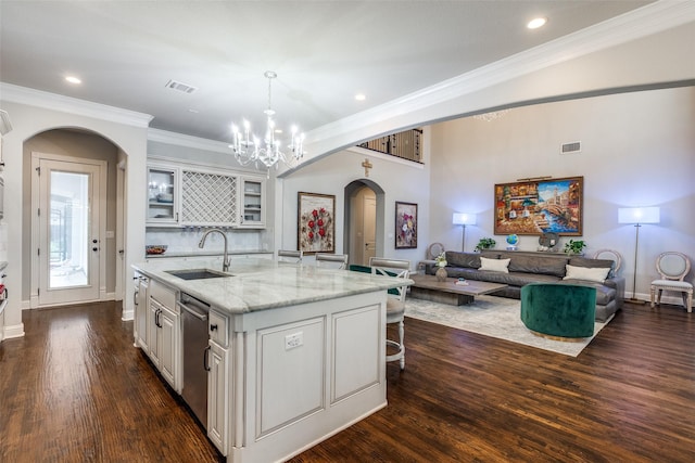 1110 Holford Dr, Frisco, TX 75036 - kitchen featuring dark wood-style flooring, an island with sink, arched walkways, a sink, and dishwasher