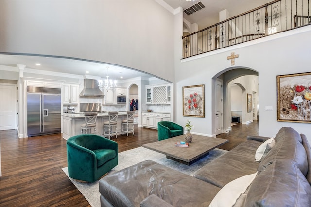 1110 Holford Dr, Frisco, TX 75036 - living room featuring visible vents, crown molding, dark wood-style flooring, a towering ceiling, and arched walkways