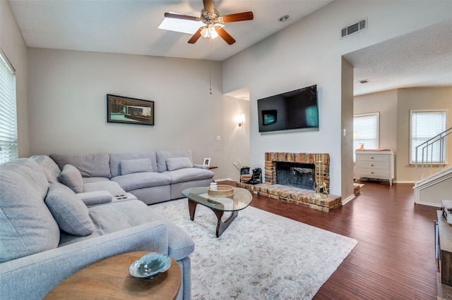 living room featuring ceiling fan, a fireplace, lofted ceiling, visible vents, and dark wood-style floors