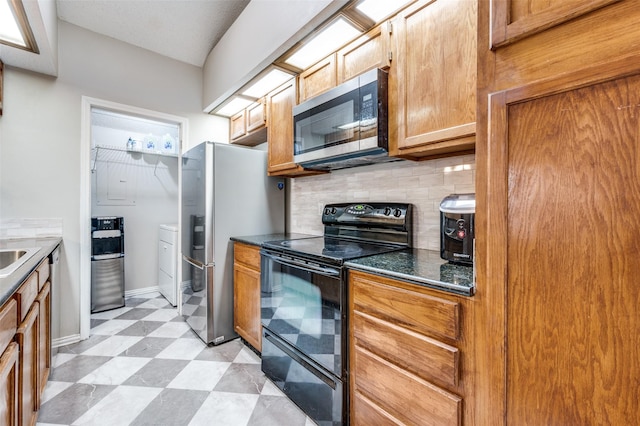 kitchen with dark countertops, light floors, washing machine and clothes dryer, tasteful backsplash, and stainless steel appliances