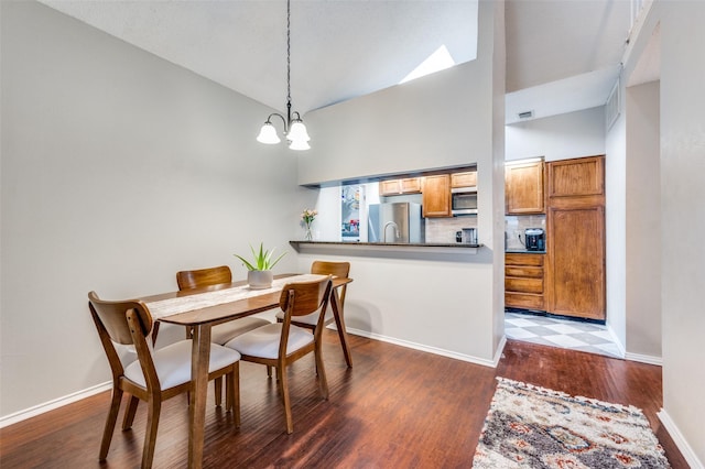 dining space featuring visible vents, wood finished floors, baseboards, high vaulted ceiling, and a notable chandelier