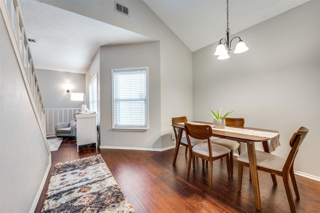 dining room featuring a chandelier, hardwood / wood-style flooring, visible vents, and lofted ceiling