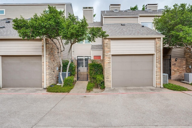 multi unit property with central air condition unit, a gate, a chimney, and roof with shingles