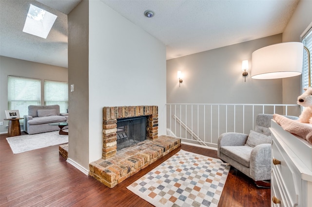 living room with a skylight, a fireplace, dark wood finished floors, and a textured ceiling