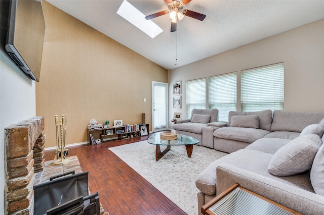 living room with a ceiling fan, a skylight, wood finished floors, high vaulted ceiling, and baseboards