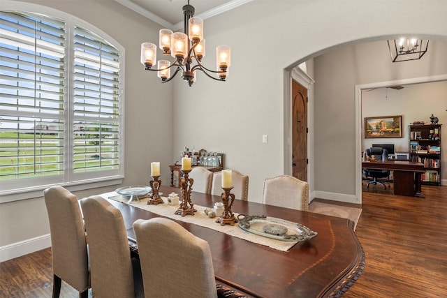 dining space with crown molding, arched walkways, a chandelier, baseboards, and wood finished floors