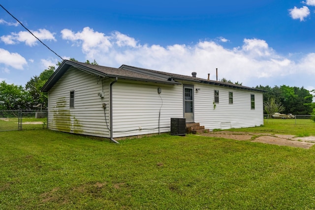 back of house featuring a lawn, fence, central AC unit, and a gate