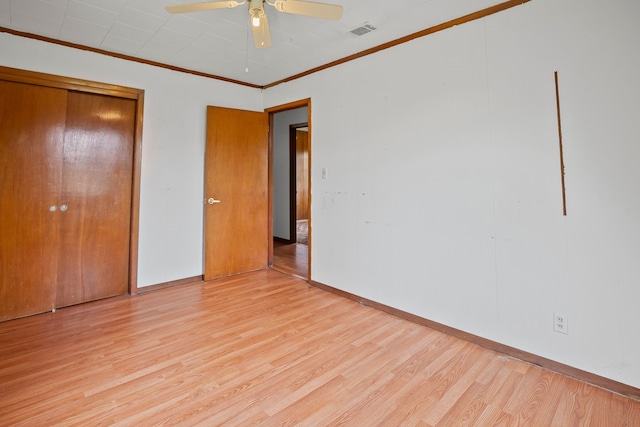 unfurnished bedroom with visible vents, ornamental molding, a closet, baseboards, and light wood-type flooring