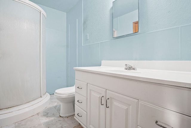 full bathroom with vanity, marble finish floor, a textured wall, toilet, and a stall shower