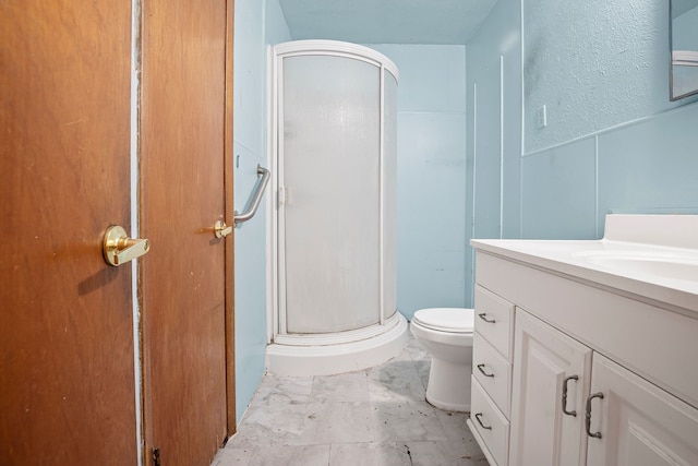 bathroom featuring a stall shower, vanity, a wainscoted wall, toilet, and marble finish floor