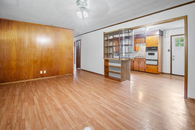 unfurnished living room with crown molding, baseboards, a ceiling fan, and light wood-style flooring