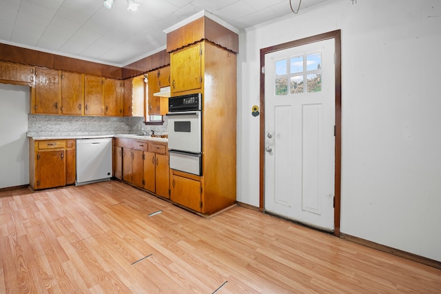 kitchen featuring decorative backsplash, brown cabinetry, light countertops, light wood-style floors, and white appliances