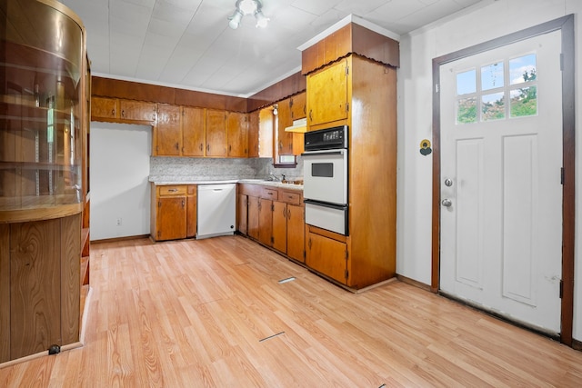 kitchen featuring brown cabinets, light countertops, light wood-style floors, a warming drawer, and white appliances