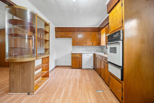kitchen featuring brown cabinetry, open shelves, white appliances, light wood-style flooring, and a warming drawer