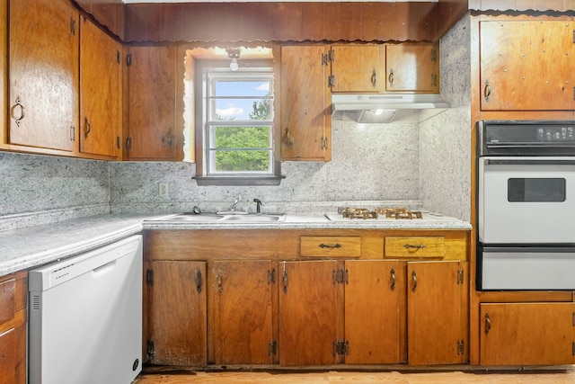 kitchen featuring white appliances, light countertops, under cabinet range hood, a sink, and a warming drawer