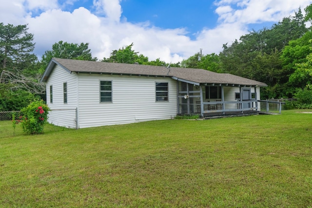 rear view of house with a lawn, a shingled roof, and fence