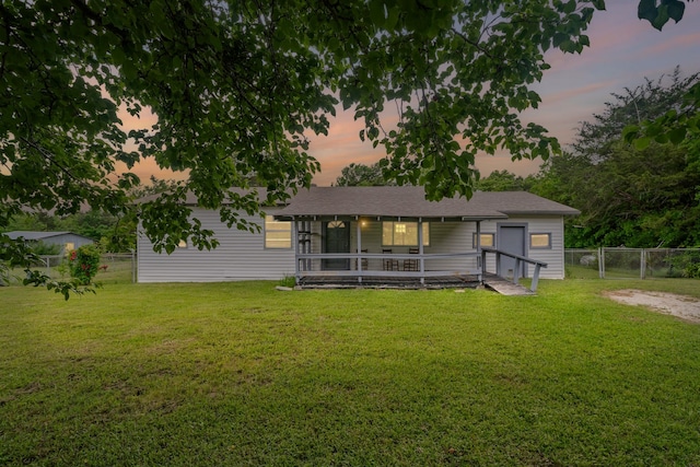 rear view of property with a lawn, fence, a gate, and a sunroom