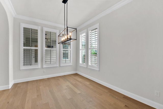 unfurnished dining area with crown molding, baseboards, wood finished floors, and a notable chandelier