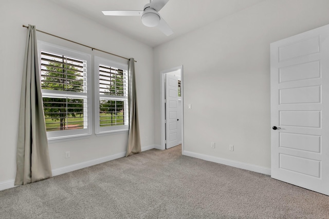 carpeted spare room featuring baseboards and ceiling fan