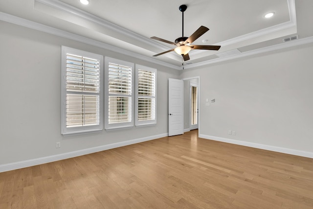 empty room with crown molding, a tray ceiling, and ceiling fan
