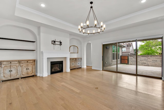 unfurnished living room with a glass covered fireplace, arched walkways, wood finished floors, and a notable chandelier