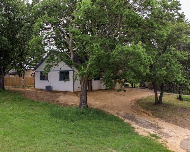 view of yard featuring dirt driveway, fence, and cooling unit